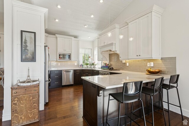 3922 View Pointe Dr, Park City, UT 84098 - kitchen with appliances with stainless steel finishes, a peninsula, white cabinets, dark wood-style flooring, and decorative backsplash