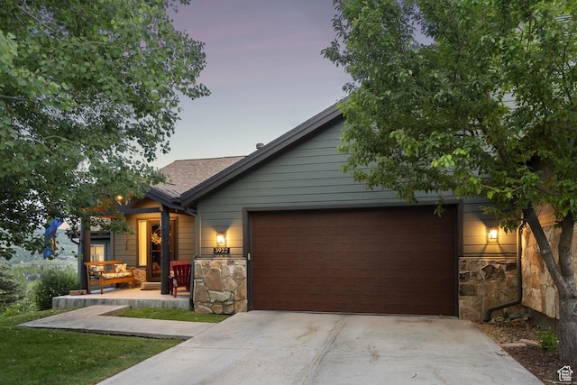 3922 View Pointe Dr, Park City, UT 84098 - view of front of home featuring stone siding, an attached garage, concrete driveway, covered porch, and a shingled roof