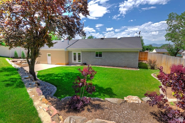 7669 S 1130 E, Midvale, UT 84047 - back of property with a fenced backyard, brick siding, a patio area, and french doors