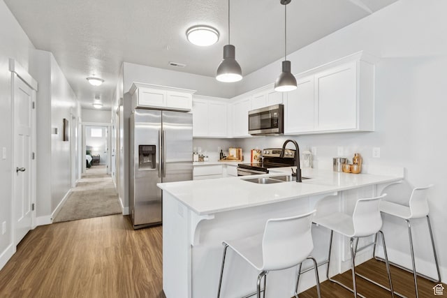 14654 S Bloom Dr W Unit K301, Herriman, UT 84096 - kitchen featuring appliances with stainless steel finishes, a peninsula, light countertops, white cabinetry, and wood finished floors