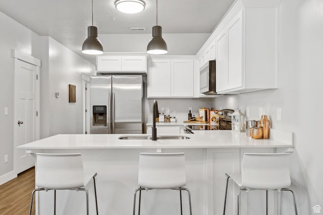 14654 S Bloom Dr W Unit K301, Herriman, UT 84096 - kitchen featuring stainless steel appliances, white cabinets, a peninsula, wood finished floors, and light countertops