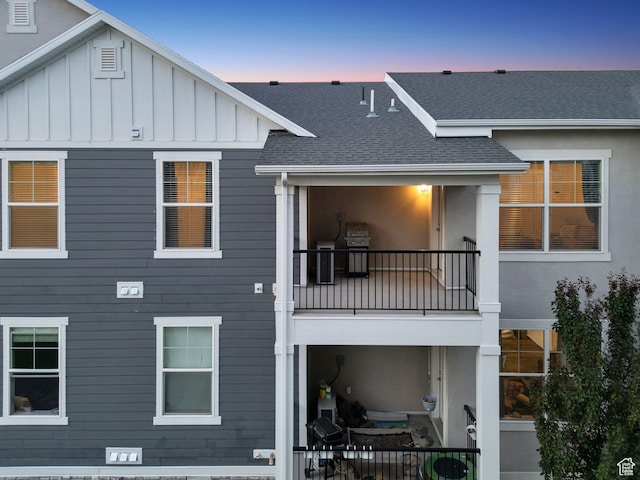 14654 S Bloom Dr W Unit K301, Herriman, UT 84096 - back of house at dusk featuring a balcony, roof with shingles, and board and batten siding