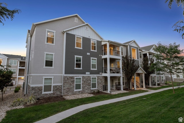 14654 S Bloom Dr W Unit K301, Herriman, UT 84096 - rear view of property featuring stone siding, stucco siding, a lawn, and board and batten siding