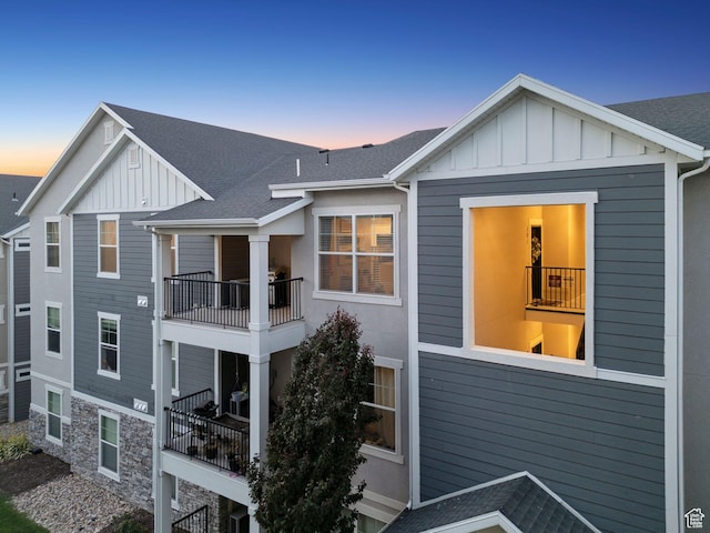 14654 S Bloom Dr W Unit K301, Herriman, UT 84096 - back of property at dusk with board and batten siding, a balcony, and roof with shingles