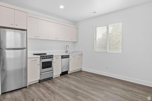 1046 W Albion Meadow Way, Bluffdale, UT 84065 - kitchen with appliances with stainless steel finishes, light countertops, light wood-type flooring, recessed lighting, and white cabinets