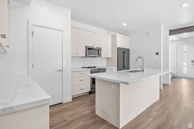 1046 W Albion Meadow Way, Bluffdale, UT 84065 - kitchen with appliances with stainless steel finishes, light wood-style floors, recessed lighting, backsplash, and a kitchen island with sink