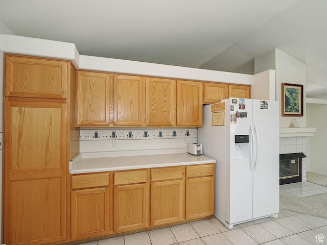 3988 W Sugar Beet Dr S, West Valley City, UT 84120 - kitchen featuring white fridge with ice dispenser, light tile patterned floors, light countertops, a tiled fireplace, and lofted ceiling