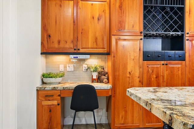1655 W 2200 S, College Ward, UT 84339 - kitchen featuring built in study area, decorative backsplash, light stone countertops, and brown cabinetry