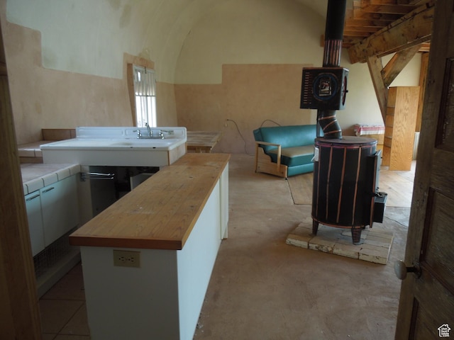 313 W Holyoak Ln, Castle Valley, UT 84532 - kitchen with butcher block counters, lofted ceiling, concrete floors, white cabinets, and a wood stove