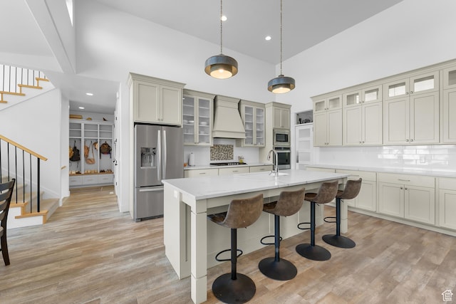 1872 S 250 W, Lehi, UT 84043 - kitchen featuring appliances with stainless steel finishes, high vaulted ceiling, custom range hood, a kitchen island with sink, and a kitchen breakfast bar