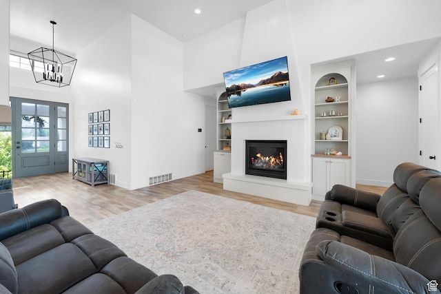 1872 S 250 W, Lehi, UT 84043 - living area featuring wood finished floors, a towering ceiling, a chandelier, a glass covered fireplace, and recessed lighting