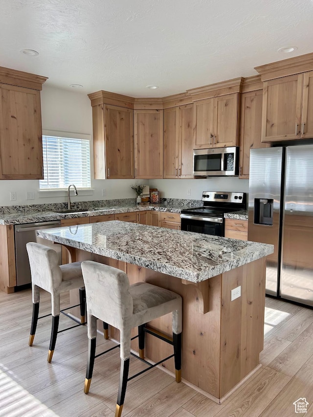 4728 E Lake Corner Dr, Eagle Mountain, UT 84005 - kitchen featuring appliances with stainless steel finishes, light wood finished floors, a breakfast bar area, a center island, and recessed lighting