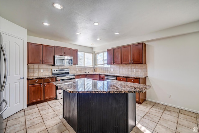 4689 W Nebo Dr S, West Jordan, UT 84088 - kitchen featuring appliances with stainless steel finishes, dark stone counters, decorative backsplash, light tile patterned floors, and recessed lighting