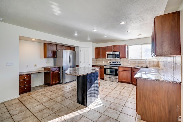 4689 W Nebo Dr S, West Jordan, UT 84088 - kitchen featuring appliances with stainless steel finishes, decorative backsplash, light stone counters, light tile patterned flooring, and a center island