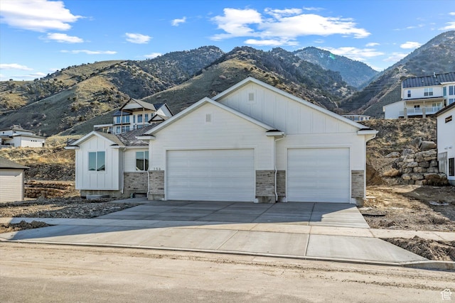 156 N Sherwood Dr, Providence, UT 84332 - view of front of property with board and batten siding, a garage, a mountain view, concrete driveway, and stone siding