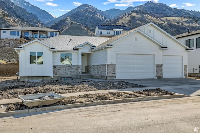 156 N Sherwood Dr, Providence, UT 84332 - view of front of home featuring board and batten siding, a garage, driveway, a mountain view, and stone siding