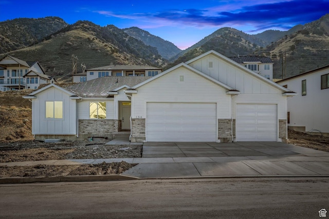 156 N Sherwood Dr, Providence, UT 84332 - view of front of home featuring board and batten siding, a garage, driveway, and a mountain view