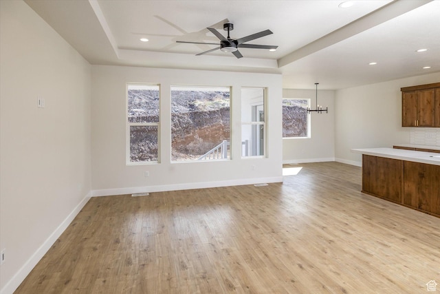 156 N Sherwood Dr, Providence, UT 84332 - unfurnished living room with a raised ceiling, light wood-style flooring, a chandelier, a ceiling fan, and recessed lighting