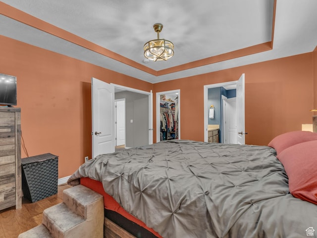 6238 W 8235 S, West Jordan, UT 84084 - bedroom featuring wood finished floors, a chandelier, a raised ceiling, and a walk in closet