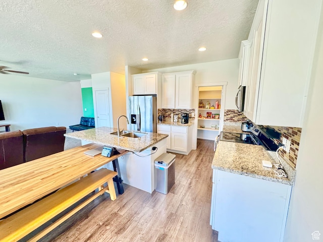 5923 W 8170 S Unit U102, West Jordan, UT 84081 - kitchen featuring stainless steel appliances, open floor plan, a textured ceiling, white cabinets, and backsplash