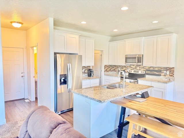 5923 W 8170 S Unit U102, West Jordan, UT 84081 - kitchen with stainless steel appliances, tasteful backsplash, white cabinetry, a textured ceiling, and recessed lighting