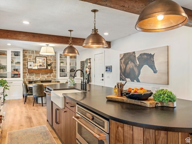 9714 S Buttonwood Dr E, Sandy, UT 84092 - kitchen with dark countertops, beam ceiling, light wood finished floors, recessed lighting, and a center island with sink