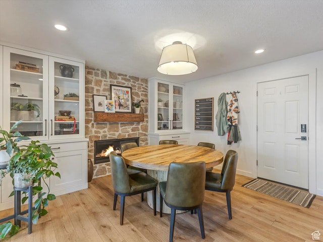 9714 S Buttonwood Dr E, Sandy, UT 84092 - dining area with a stone fireplace, light wood-style flooring, and recessed lighting