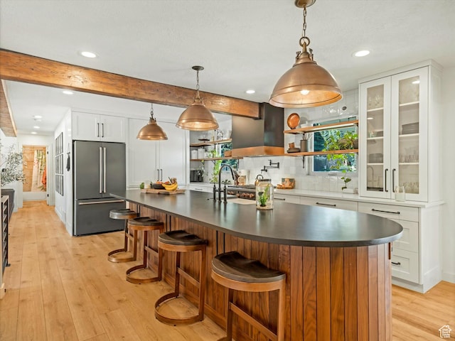 9714 S Buttonwood Dr E, Sandy, UT 84092 - kitchen featuring high end refrigerator, dark countertops, light wood-style flooring, backsplash, and white cabinetry