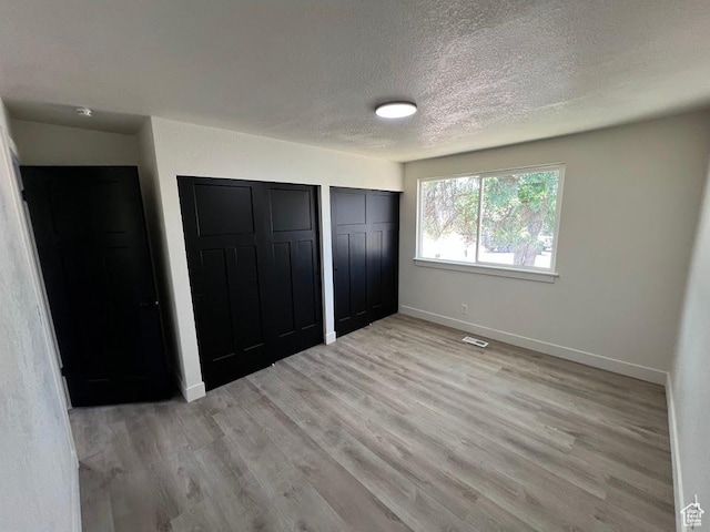 1569 E Boysenberry Cir S, Sandy, UT 84093 - unfurnished bedroom with a textured ceiling, two closets, and light wood-type flooring