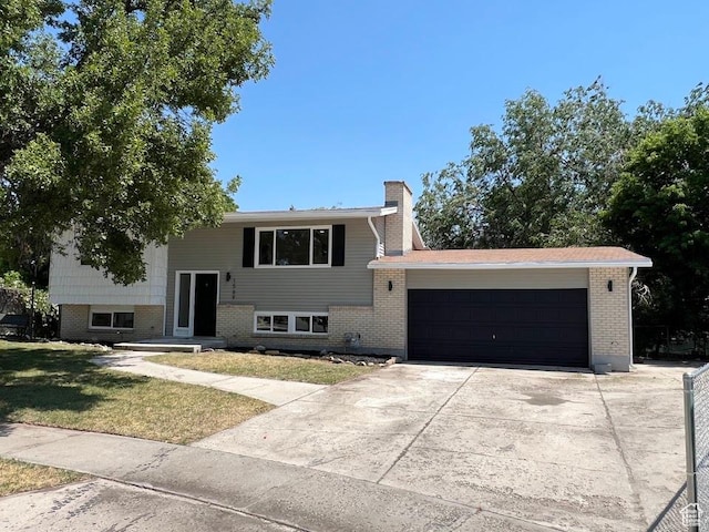 1569 E Boysenberry Cir S, Sandy, UT 84093 - split foyer home with an attached garage, driveway, a chimney, brick siding, and a front lawn