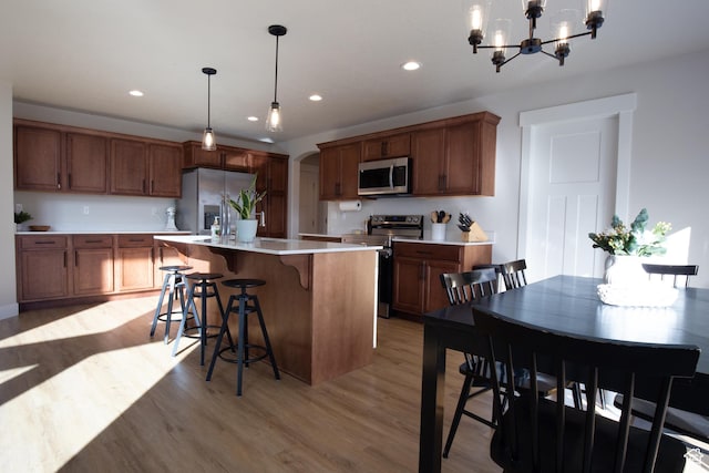 922 Olson Dr N, Saratoga Springs, UT 84045 - kitchen with stainless steel appliances, light countertops, a chandelier, light wood-style flooring, and an island with sink