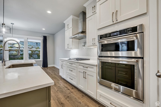 2508 E Lone Hill Dr, Draper Ut Cnty, UT 84020 - kitchen featuring wall chimney exhaust hood, stainless steel appliances, tasteful backsplash, white cabinetry, and wood finished floors