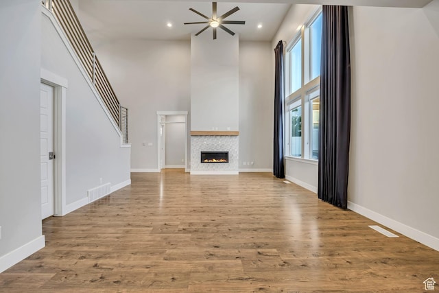 2508 E Lone Hill Dr, Draper Ut Cnty, UT 84020 - unfurnished living room with a high ceiling, ceiling fan, a tile fireplace, wood finished floors, and recessed lighting