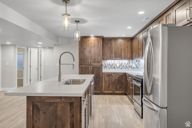 2508 E Lone Hill Dr, Draper Ut Cnty, UT 84020 - kitchen with stainless steel appliances, light wood finished floors, a center island with sink, light countertops, and hanging light fixtures