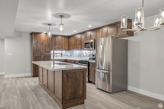 2508 E Lone Hill Dr, Draper Ut Cnty, UT 84020 - kitchen featuring stainless steel appliances, light wood finished floors, light countertops, a center island with sink, and pendant lighting