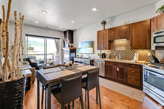 6169 E Park Ln S Unit 30, Park City, UT 84098 - kitchen featuring appliances with stainless steel finishes, decorative backsplash, light wood finished floors, light stone counters, and recessed lighting