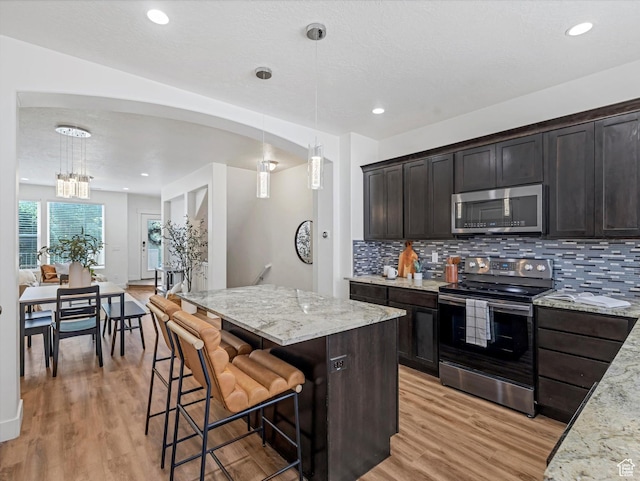 4851 W Daybreak Pkwy, South Jordan, UT 84009 - kitchen with stainless steel appliances, decorative backsplash, light wood finished floors, light stone countertops, and recessed lighting