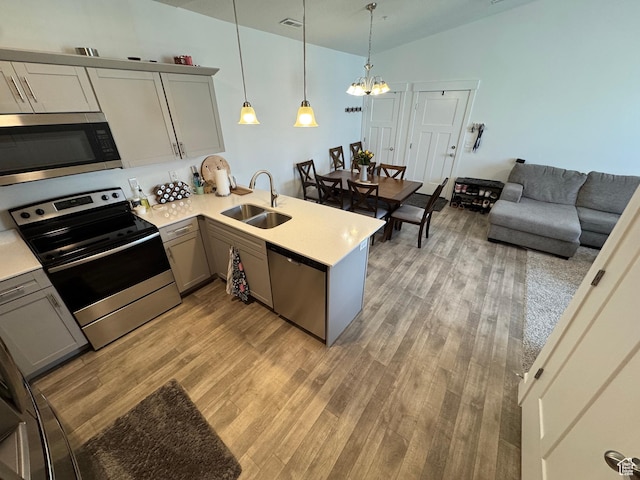 949 W Big Ben Ln Unit I304, Saratoga Springs, UT 84045 - kitchen with stainless steel appliances, a peninsula, a chandelier, and light wood-type flooring