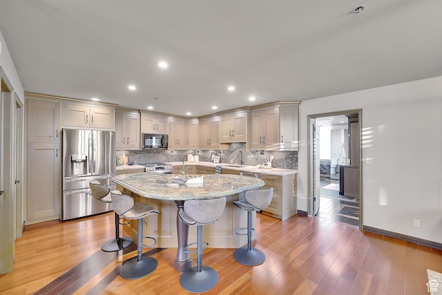 44 W Broadway S Unit 2005S, Salt Lake City, UT 84101 - kitchen featuring stainless steel appliances, a breakfast bar area, decorative backsplash, light wood-type flooring, and recessed lighting