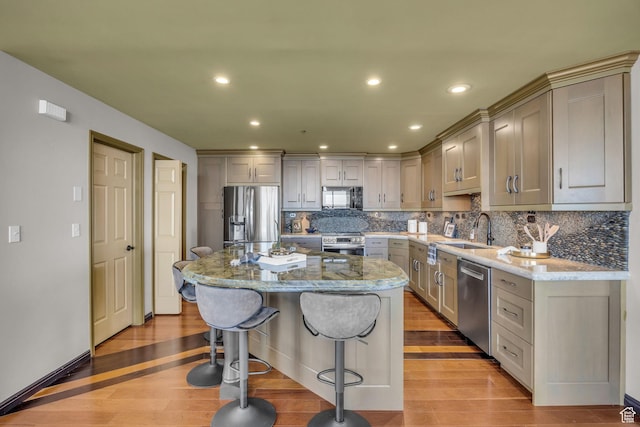 44 W Broadway S Unit 2005S, Salt Lake City, UT 84101 - kitchen featuring appliances with stainless steel finishes, light wood-type flooring, a kitchen bar, light stone countertops, and a center island