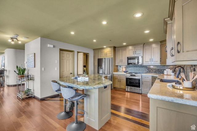 44 W Broadway S Unit 2005S, Salt Lake City, UT 84101 - kitchen featuring stainless steel appliances, hardwood / wood-style floors, a center island, a breakfast bar, and light stone countertops