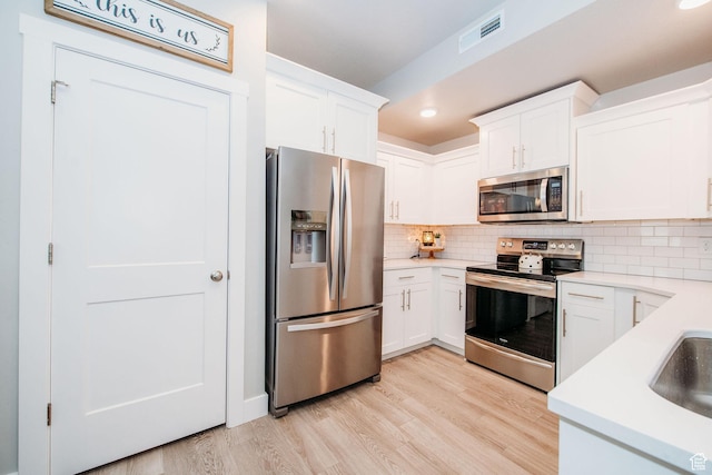 2726 S 2250 W Unit 218, West Haven, UT 84401 - kitchen with appliances with stainless steel finishes, light wood-type flooring, light countertops, white cabinets, and backsplash