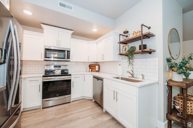 2726 S 2250 W Unit 218, West Haven, UT 84401 - kitchen featuring appliances with stainless steel finishes, light countertops, white cabinets, light wood-style floors, and tasteful backsplash
