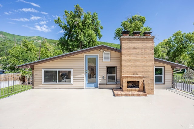 32 S Smokey Ln, Emigration Canyon, UT 84108 - rear view of property featuring an outdoor brick fireplace, a patio area, and a chimney