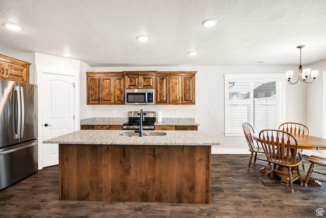 824 N 980 W, Tremonton, UT 84337 - kitchen with stainless steel appliances, light stone counters, an island with sink, a textured ceiling, and recessed lighting