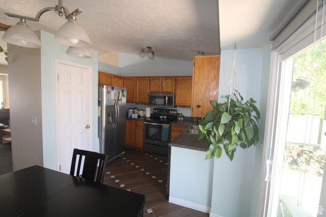 423 W 180 N, Clearfield, UT 84015 - kitchen featuring appliances with stainless steel finishes, dark countertops, dark wood-type flooring, and brown cabinets