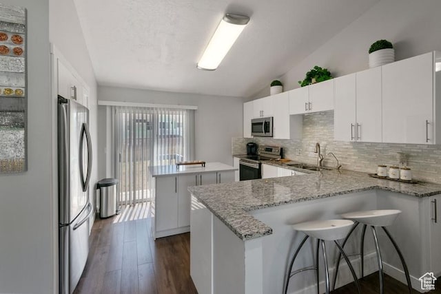 4015 S Brandon Ct, West Valley City, UT 84128 - kitchen featuring stainless steel appliances, vaulted ceiling, a peninsula, backsplash, and a kitchen island