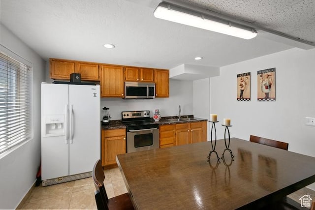 4015 S Brandon Ct, West Valley City, UT 84128 - kitchen with appliances with stainless steel finishes, dark countertops, brown cabinets, recessed lighting, and light tile patterned floors