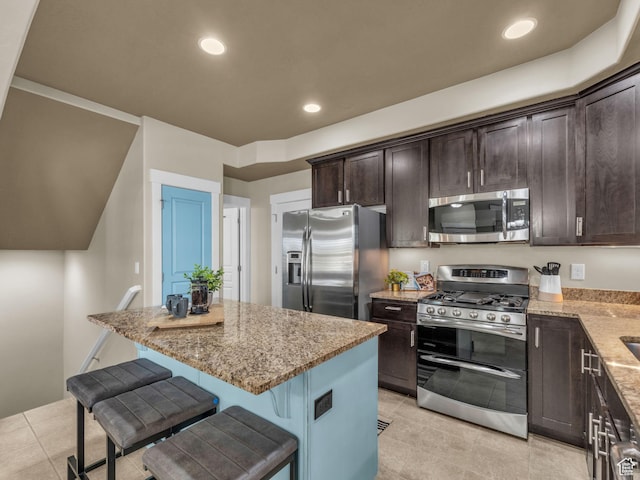 4956 W Vermillion Dr, South Jordan, UT 84009 - kitchen featuring stainless steel appliances, light stone countertops, dark brown cabinets, a kitchen island, and a kitchen bar