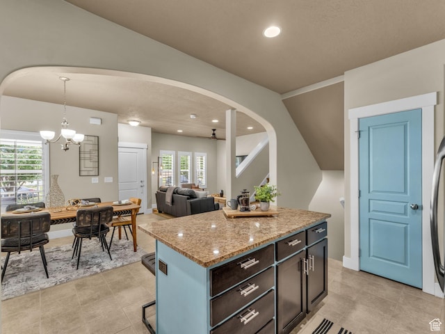 4956 W Vermillion Dr, South Jordan, UT 84009 - kitchen with arched walkways, a chandelier, light stone counters, hanging light fixtures, and recessed lighting